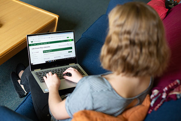 Student using the uwgb libraries site on her laptop