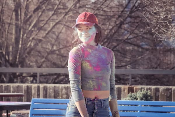 Female student smiles while full of colorful powder from the Hala Festival.