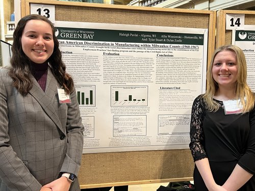 Two students standing by project