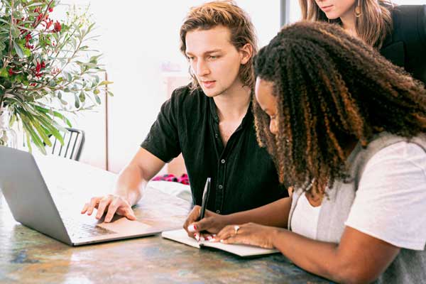 Two coworkers work together at desk