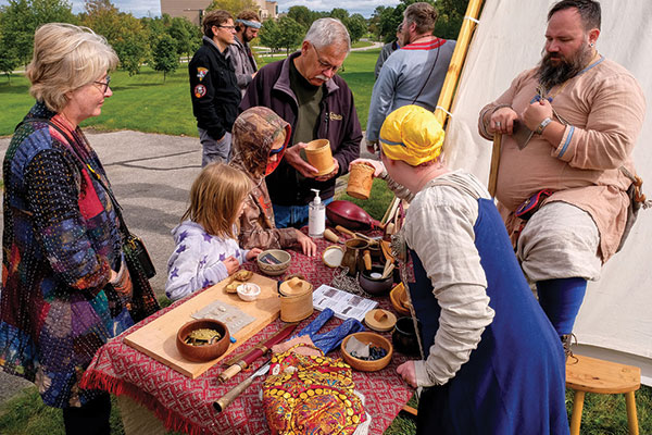 Children crowd around a table with beads to make bracelets.