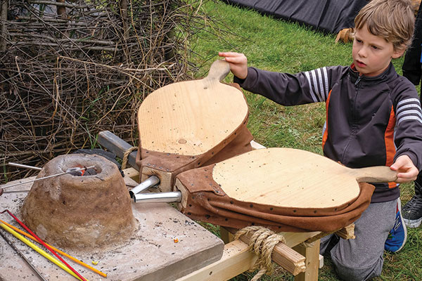 A child using a pair of bellows.