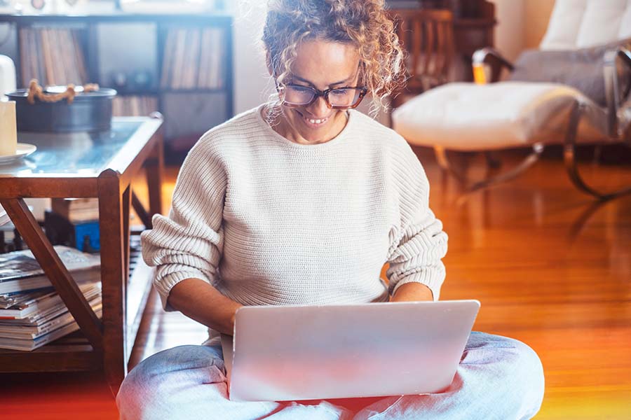 woman sitting on floor looking at laptop screen