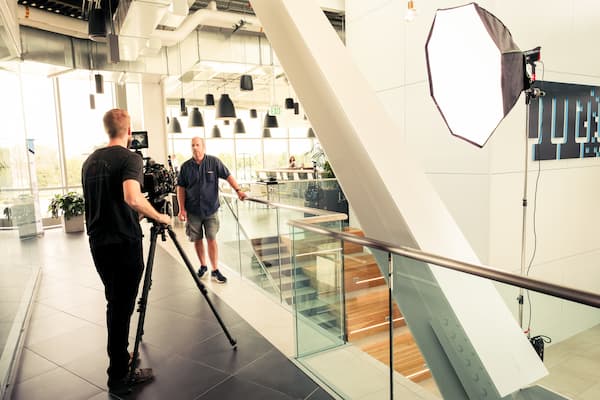 A camera crew sets up near a second floor staircase.
