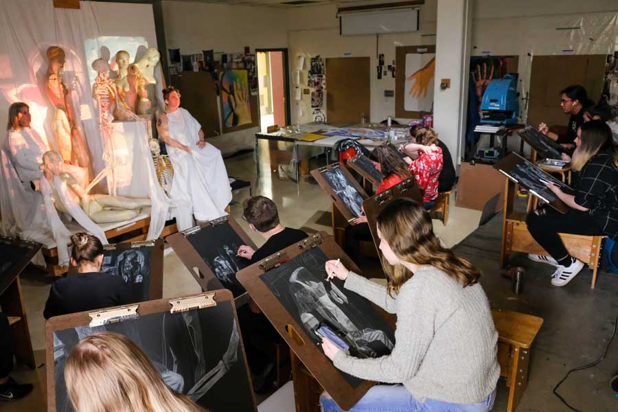 Students draw live models in figure drawing studio