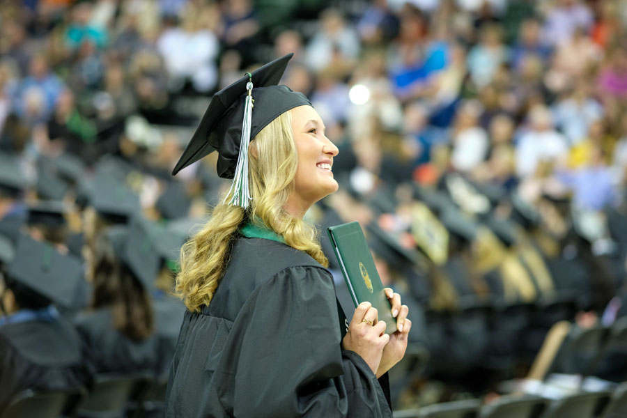 Student holds up diploma at graduation
