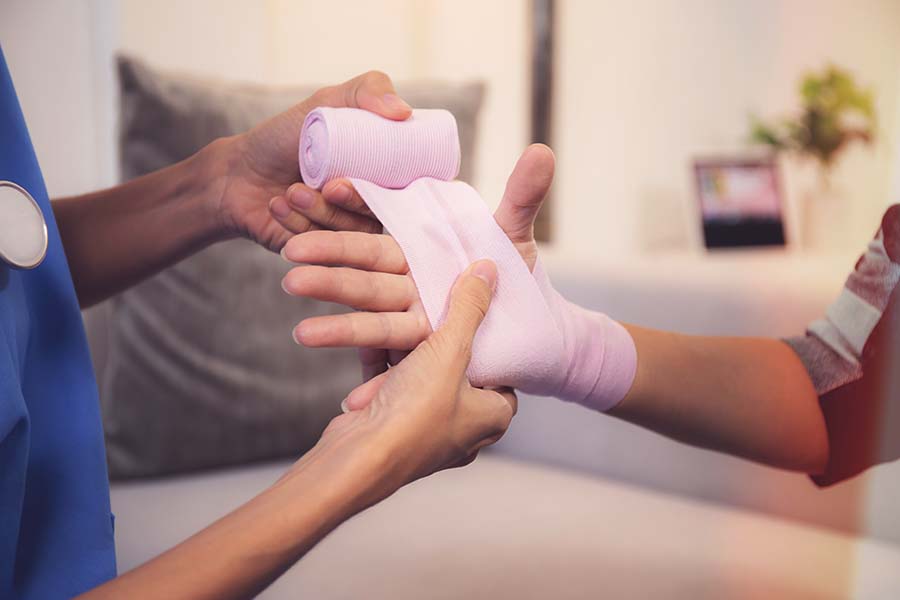 caregiver wrapping a patient's injured hand