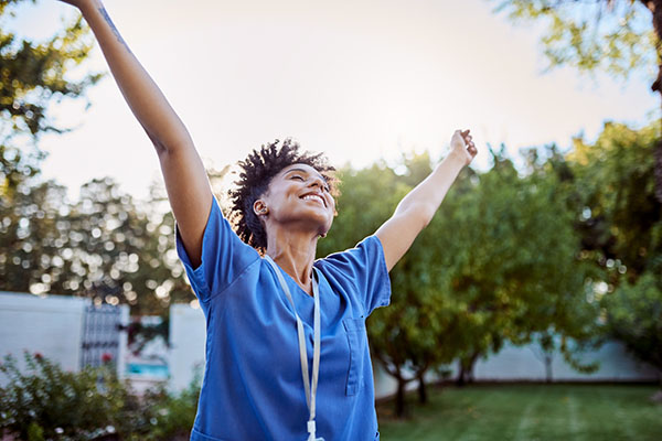 Happy medical worker outside with her arms up