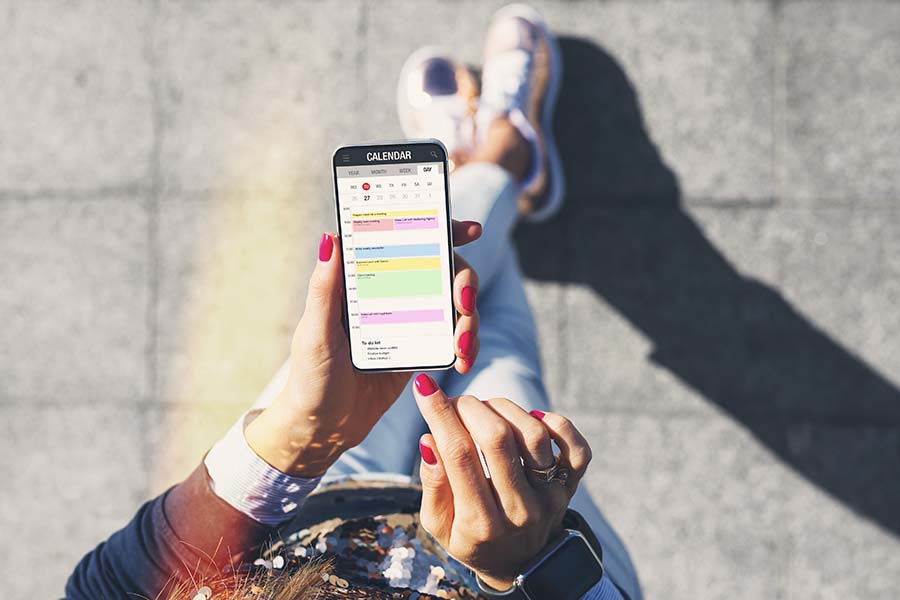 woman outside scheduling calendar event on phone