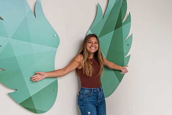 Una estudiante posa delante de las alas de fénix foto opp